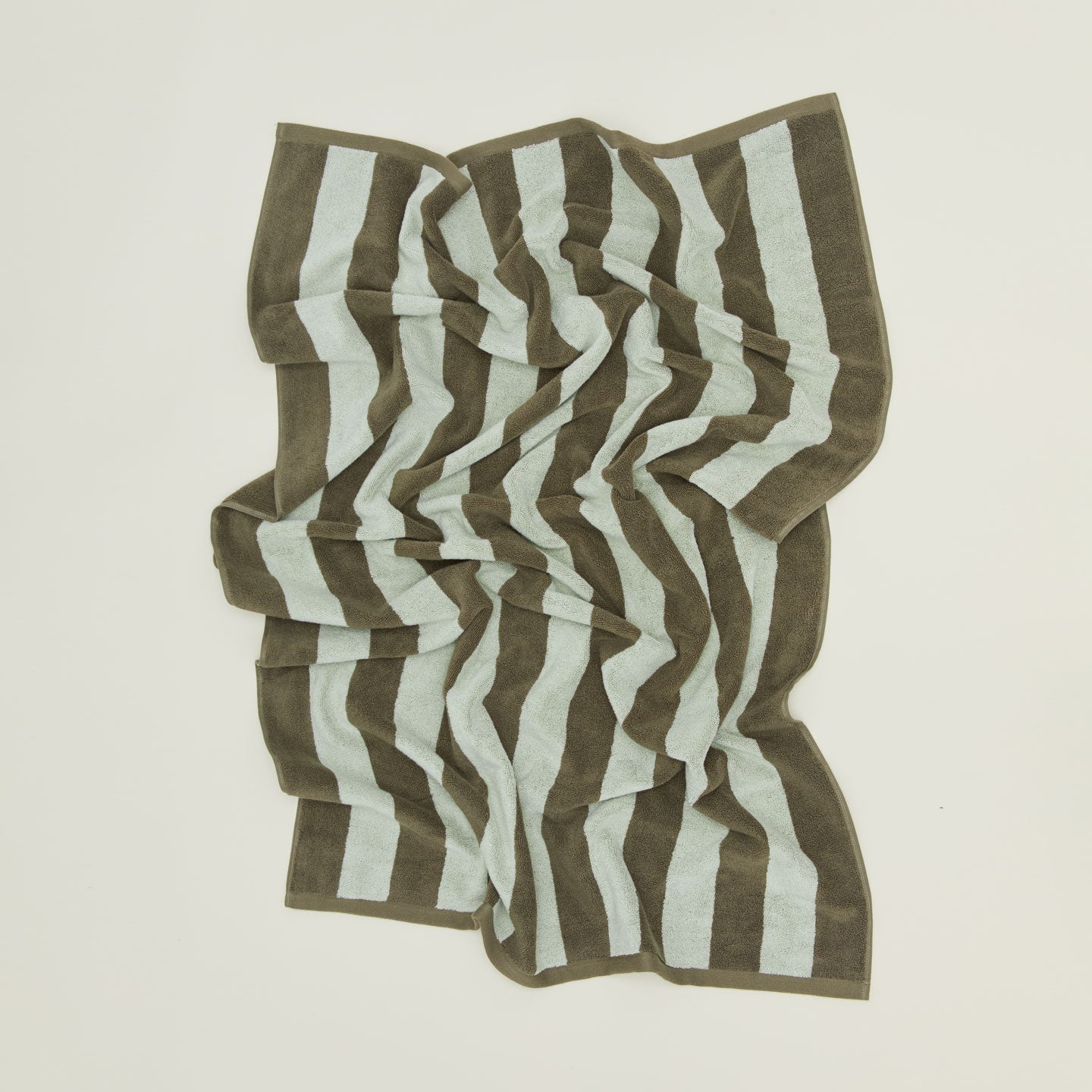 An overhead of a striped light grey and dark grey terry bath towel.